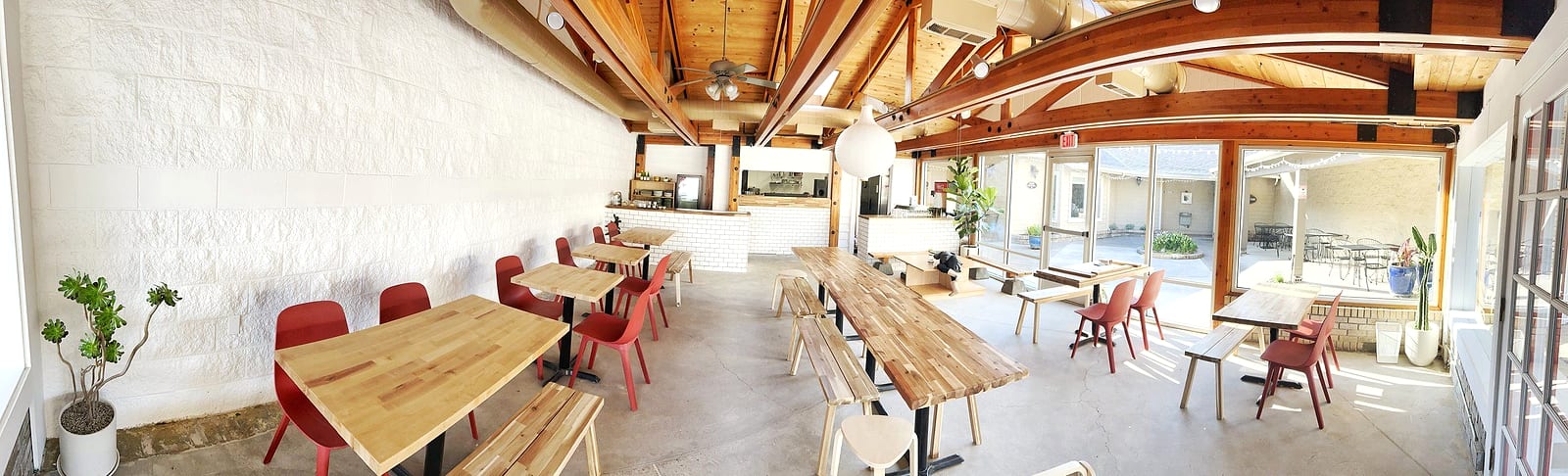 Bright, airy dining room with wood beams, wooden tables and red chairs